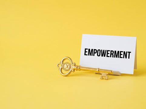 Golden key next to white card reading empowerment on yellow background suitable for business content representing success potential and growth
