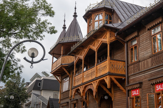 Distinctive traditional wooden building showcasing multiple ornate balconies, intricate carvings, and unique roofline elements in Zakopane, Poland.