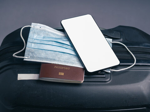 Smartphone mockup with face mask and passport on suitcase