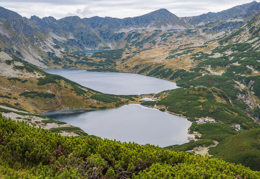 A rustic mountain hut sits peacefully in Valley of Five Polish Lakes (Dolina Pieciu Stawow Polskich), framed by rocky slopes and dwarf pines in the Tatras Mountains in Zakopane, Poland.