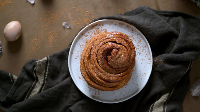 Freshly Baked Cinnamon Roll on a White Plate with Rustic Decor