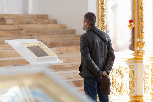 A man stands before an icon in a church