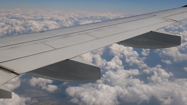 Aerial view with airplane wing during flight above the clouds.