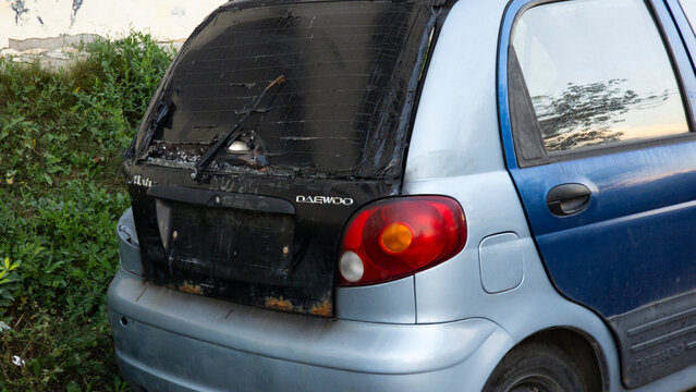 Damaged rear of an older Daewoo Matiz with a visibly patched rear window, worn bodywork and signs of deterioration, illustrating car repair, neglect and aging transportation