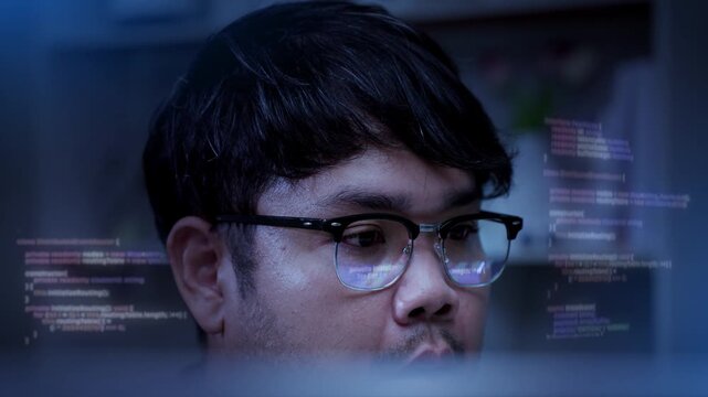 Asian software developer reviewing computer code on monitor with skeptical facial expression and eye reflection in office