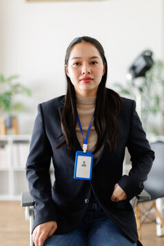 Asian businesswoman showing identity card, feeling confident and professional, ready for her corporate career in a modern office, representing employment and business success