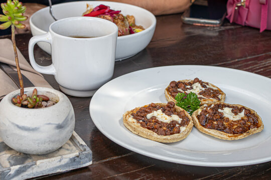 Breakfast with bean sopes and coffee on a wooden table in Comala, Mexico