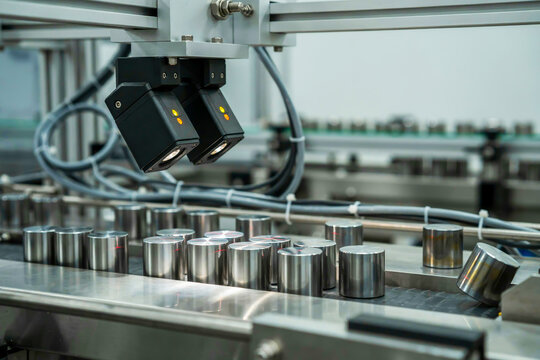 Automated quality control camera system inspecting metal cylindrical parts on a moving manufacturing assembly line