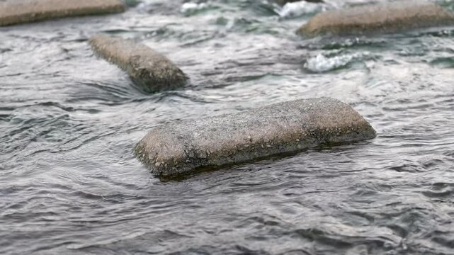 浅瀬の岩を越える水の流れ、スローモーションのクローズアップ映像