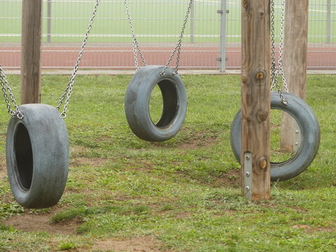 Three tire swings hanging on playground on misty morning