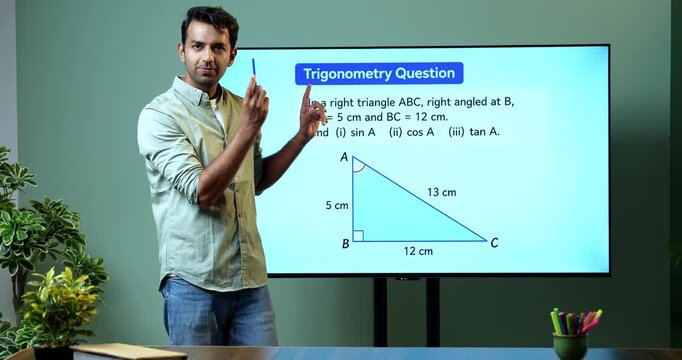 Young Indian male mathematics teacher explaining trigonometry on a large digital TV whiteboard for online classes, covering math education, geometry and modern e-learning.