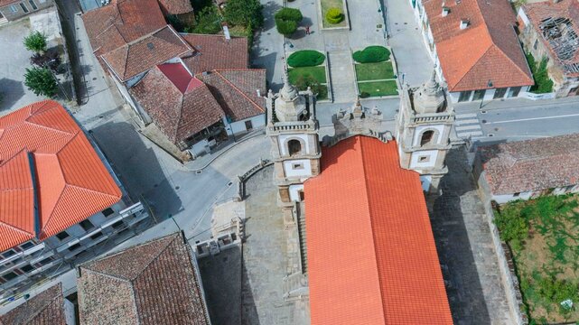 Aerial zenith view of the historic Sao Vicente Mother Church with bright red tiled roofs and stone towers in Vimioso, Braganca, North Portugal.
