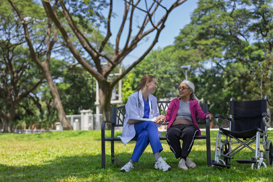 Nurse providing compassionate care to senior woman in wheelchair at outdoor park