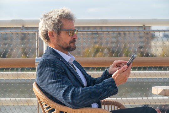 Portrait of attractive senior man with smartphone outdoor in the city