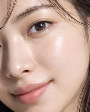 透明感のある肌とみずみずしい頬の輝きが印象的な美容写真 自然な毛穴や目元の質感と優しい微笑みを捉えたナチュラルメイクのスキンケア超接写