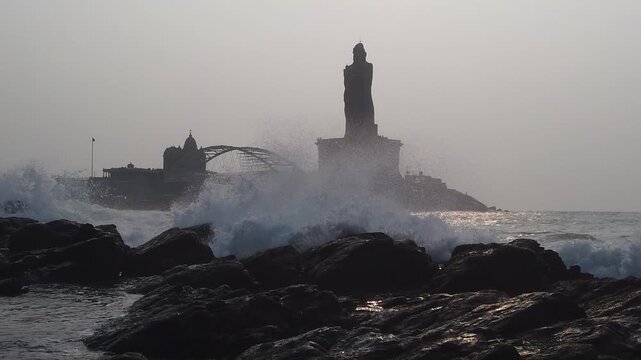 Slow motion video of powerful sea waves crashing against rocky shores near Thiruvalluvar Statue and Vivekananda Rock Memorial in Kanyakumari, India, during rough sea conditions.