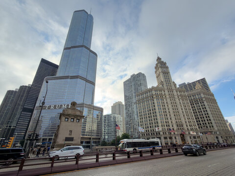 CHICAGO, IL, JUN 17, 2026: Wide-angle view from the bridge of Trump International Hotel and Tower and the Wrigley Building, with a bus, taxi and flags under a cloudy sky