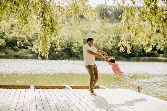 Joyful moments of a father swinging his child by the water's edge