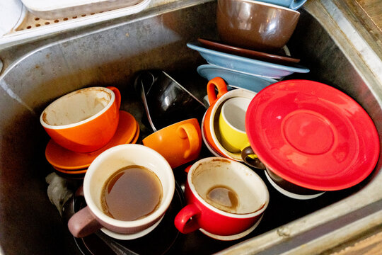 Dirty coffee cups and saucers piled in cafe sink after service