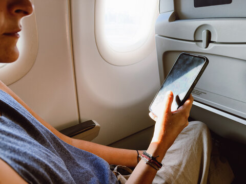 Person Using Smartphone on Airplane Seat by Window