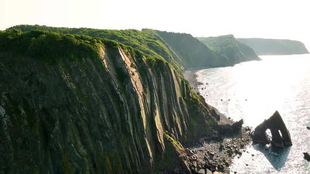 Aerial flight along Blackchurch Rock and steep Devon sea cliffs
