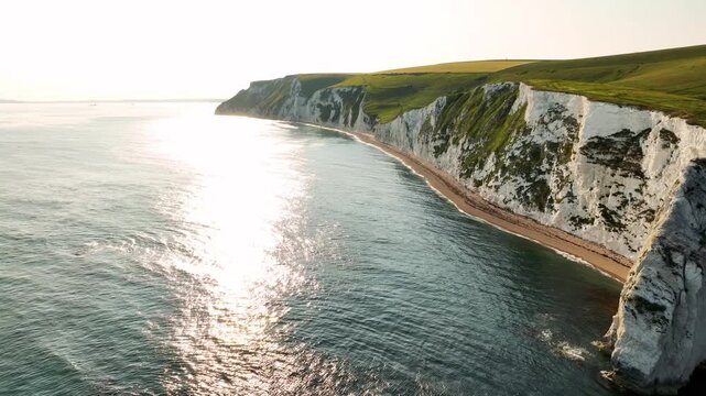 Low aerial flight over the sea toward white chalk cliffs