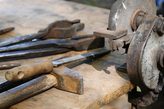 Set of traditional, well-worn workshop tools used in blacksmithing for traditional metalworking.