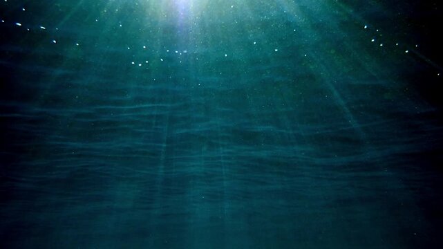 Light filtering down through blue water. Underwater sunlight in deep sea. Light viewed from blue abyss. Underwater sunlight shining deep with ripples on wave surface ocean ray, Under water Slow motion