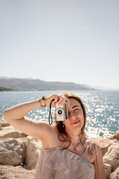 Woman with retro camera by the sunny seaside