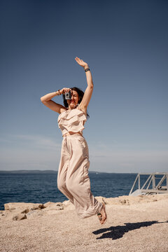 Woman with retro camera jumping by the seaside