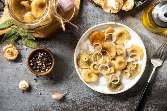 Marinated mushrooms with onion and spices on rustic table