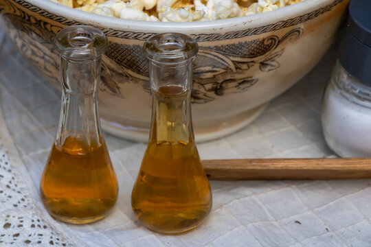 Small glass cruets with amber liquid beside decorated ceramic bowl in rustic traditional food setting