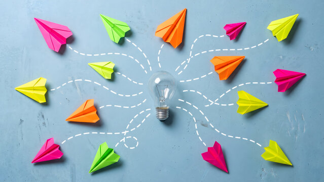 Light bulb with colorful paper airplanes flying in different directions on blue background