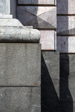 Abstract architectural shadow cast on granite base blocks and rusticated stone facade of Saint Michael Castle.