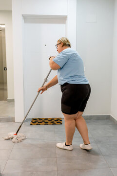 House cleaner mop tile floor in apartment hallway