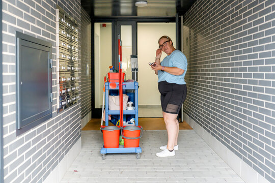 House cleaner with janitorial cart in apartment hallway