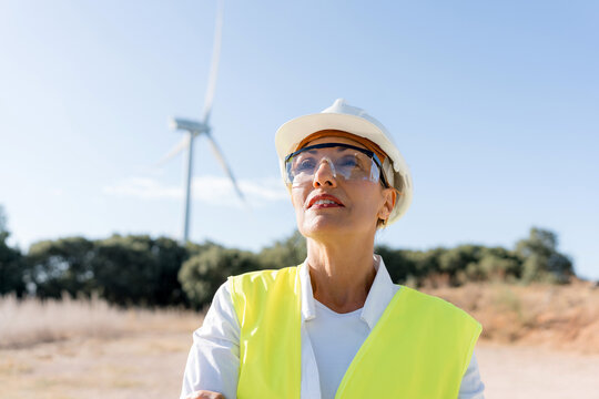 Female engineer inspecting wind turbine field for renewable energy