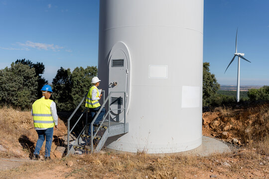 Female engineer inspect wind turbine at renewable energy site