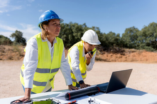 Female engineers review wind turbine data at construction site