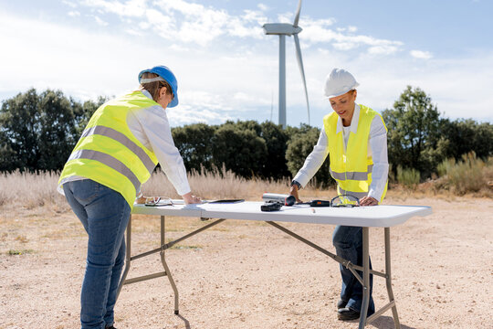 Female engineers inspect wind turbine equipment at site