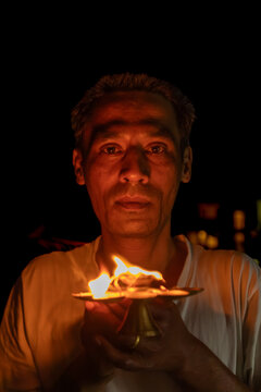 Hindu man holding oil lamp during Diwali puja ceremony