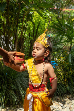 Young child in Krishna costume during Hindu festival ceremony