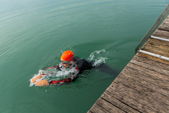 Triathlete swim beside dock during open water training
