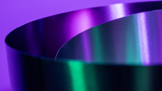 Curved metal shape with vibrant purple and green reflections