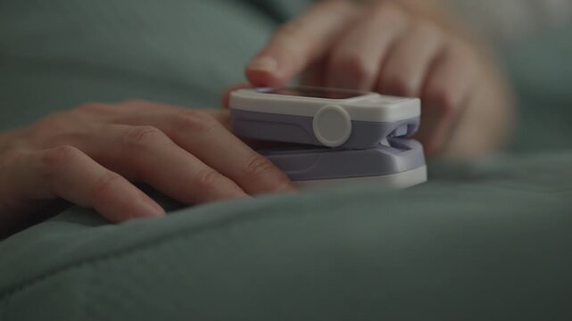 Cardiovascular, Respiratory Diseases. Woman Hand Putting Pulse Oximeter on Finger to Check Oxygen Level in Blood Lying in Bed in Bedroom. Measures Oxygen Saturation, Heart Rate and Oxygen Levels.