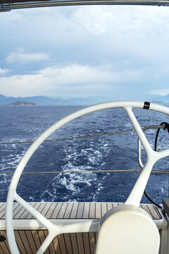 Yacht helm overlooking wake and island coastline