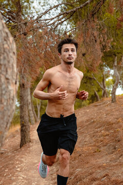 Shirtless runner exercise on forest trail in autumn