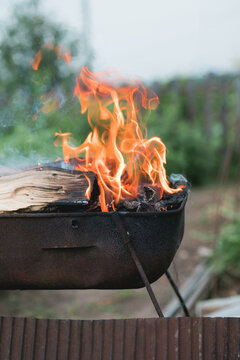 Burning firewood in charcoal grill outdoors