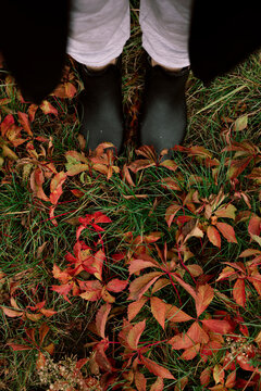 Person in black boots among fallen autumn leaves