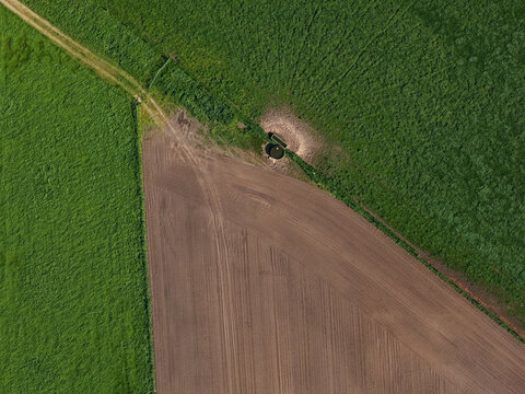Aerial view of green field and plowed farmland pattern